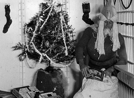 An inmate at the Orange County Jail playing Santa with a mop and paper hat, 1940s
