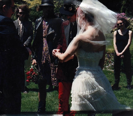 GG Allin in a dress holding a bouquet of roses at his brother Merle's wedding, 1989