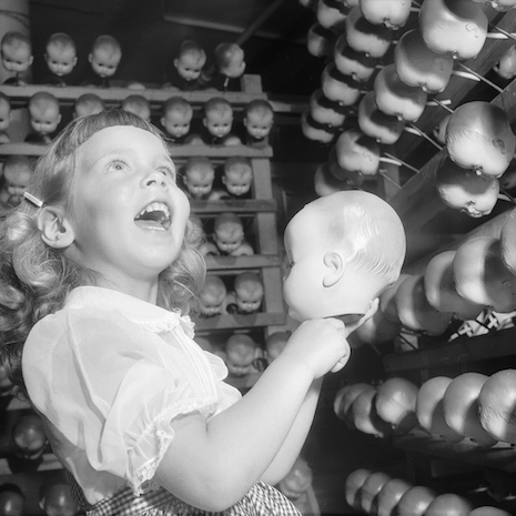 Little girl holding a doll head while others look on, Long Island, 1955