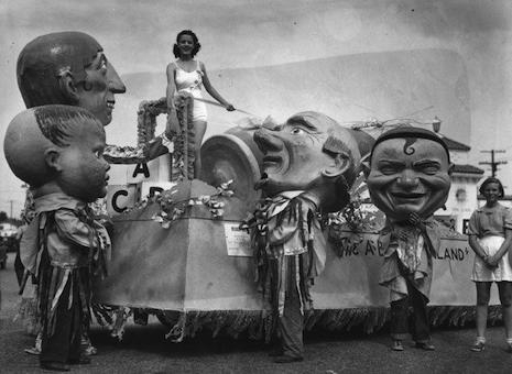 Miss California on her float surrounded by giant papier-mâché masks, mid-1930s