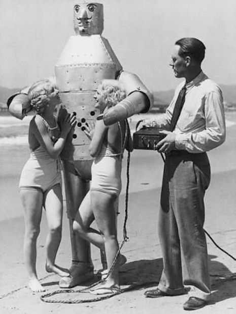 Robot at the beach with two blondes in bathingsuits, late 20s, early 30s