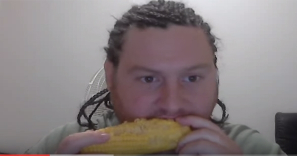 Guy with cornrows eats corn while listening to Korn