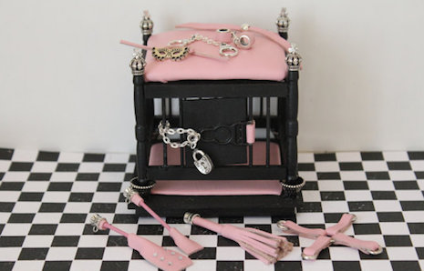 Miniature dollhouse BDSM cage with pink leather cushioning
